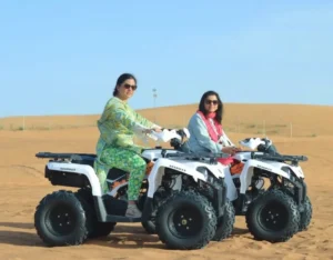 Quad bike riders traveling across red sand dunes in Lahbab Desert