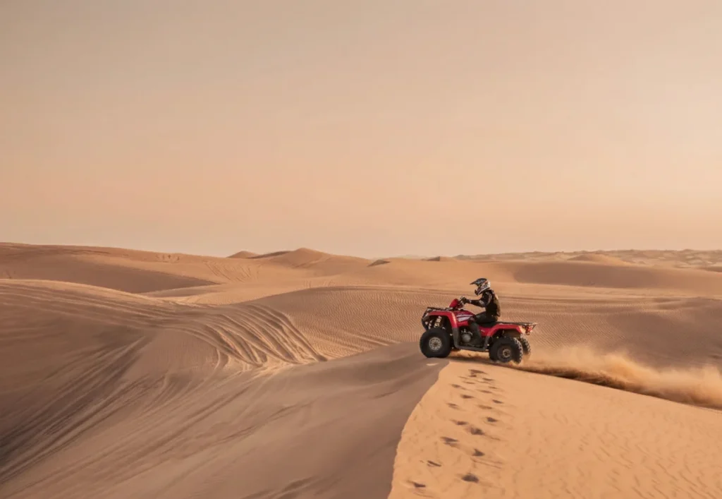 Rider crossing tall red sand dunes in the Lahbab desert area