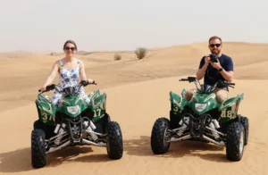 Rider navigating a quad bike across the red sand dunes of Dubai desert during a guided morning adventure under clear skies safely