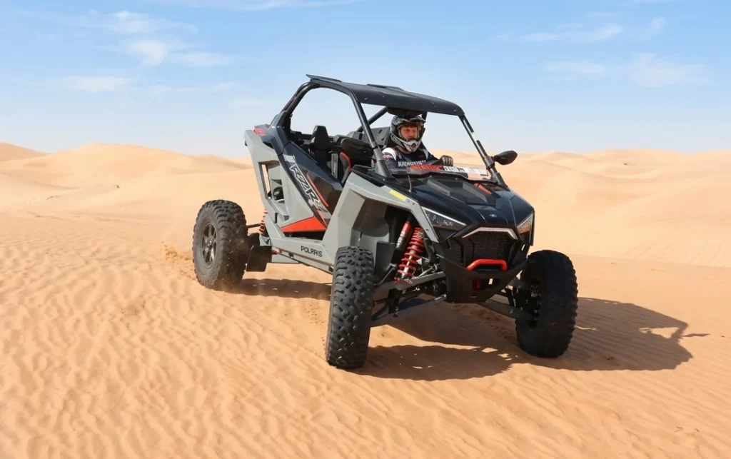 Tour guide providing helmet goggles gloves and safety instructions before dune buggy ride in Dubai desert ensuring beginner riders stay protected