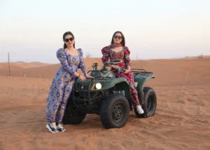 Adventure seeker enjoying quad biking across Dubai desert dunes during a guided tour with safety gear and powerful off road ATV vehicle.