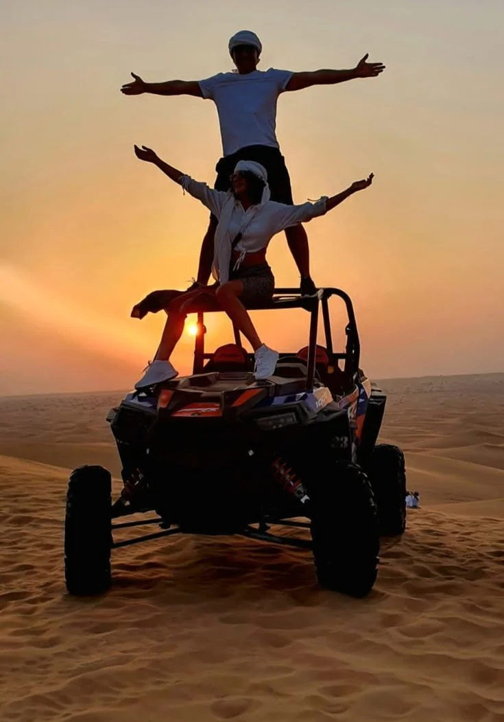 Can-Am X3 dune buggy driving across Dubai desert dunes during sunset off-road adventure tour